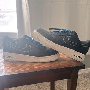 Air Force 1s black , blue laces , white Nike stitching.